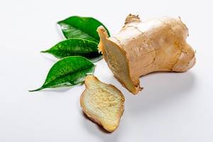 Root ginger on white background with green leaves