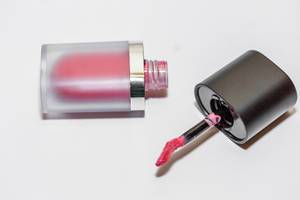 Rosaroter Lipgloss für frische Lippenfarbe liegt geöffnet auf weißem Tisch