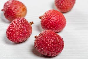 Rote Litschi Früchte auf einem weißen Holztisch