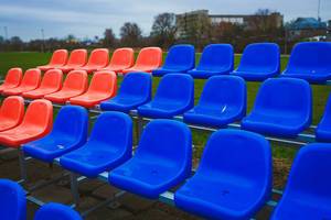 Rote und blaue Stadionsitzreihen auf einer Wiese