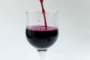 Roter Alkohol in ein Weinglas eingießen