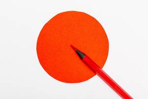 Roter Holzmalstift zeigt in einen roten Kreismittelpunkt als Symbol für genaue Entscheidungsfindung