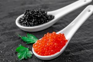 Roter Lachskaviar und schwarzer Kaviar auf einer Steinplatte in der Nahaufnahme
