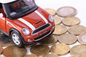 Rotes Spielzeugauto fährt auf Euro-Münzen