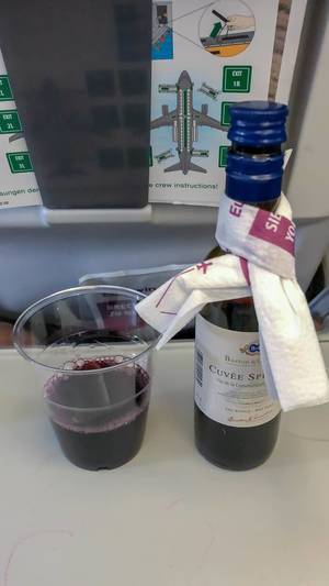 Rotwein wird mit Plastikbecher im Flugzeug auf der Flugreise als Drink serviert