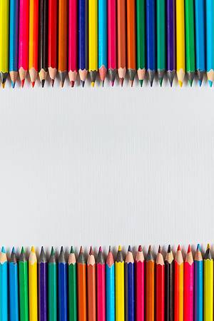 Rows of color pencils on a blank white paper