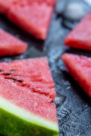 Saftige, reife Wassermelonenscheibe auf einer schwarzen Steinplatte