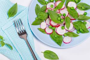 Salad with fresh Basil leaves, radishes and green peas with fork and blue tea towel (Flip 2019)