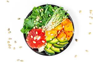 Salad with grapefruit, avocado, micro greenery and pine nuts on a white background. Top view