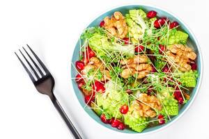 Salad with walnuts, pomegranate, watercress and vegetables on a white background, top view (Flip 2020)