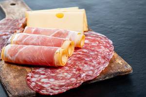 Salami, jamon, ham and cheese sliced on old kitchen wooden Board
