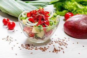 Salat mit frischen Salatblättern, Paprika, Tomaten und Mango mit Leinsamen und Joghurt