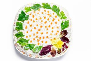 Salat mit Gemüse und Krabben-Sticks angerichtet mit frischer Petersilie, Spinatblättern und rotem Kaviar vor weißem Hintergrund Draufsicht