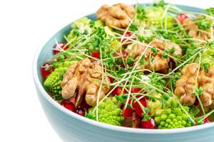 Salat mit Walnusskernen, Mikrogrün, Romanesco Kohl und Granatapfelkernen mit weißem Hintergrund Nahaufnahme