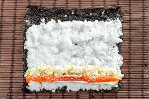 Salmon, avocado, rice on seaweed and cucumber on brown background (Flip 2019)