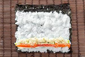Salmon, avocado, rice on seaweed and cucumber on brown background