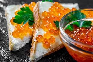 Salmon red caviar on white bread with parsley leaves