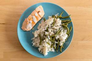 Salmon with rice and green beans on a blue plate