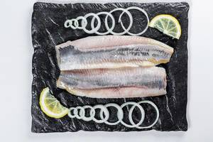 Salted herring with onion slices and lemon slices