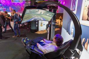 Samsung Gaming Mann sitzt in einem Gaming Stuhl mit einem Curved Fernseher vor ihm