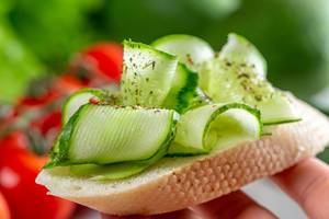 Sandwich with fresh sliced cucumber in hand close-up (Flip 2019)