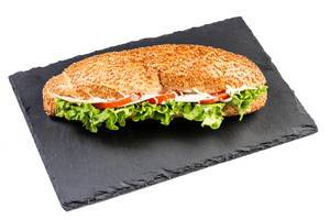 Sandwich with lettuce cheese ham and tomato on black stone tray