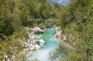 Schmale Holzbrücke über dem türkisfarbenen Fluß Soča  / Isonzo in Goriška, Slowenien