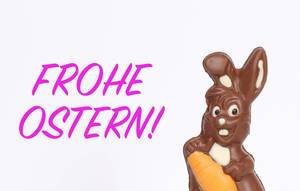 Schokoladen-Osterhase mit Text Frohe Ostern vor weißem Hintergrund