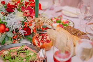 Schön dekorierter Tisch mit Roastbeef und Brot, Gläsern, Blumengesteck und grüner Kerze