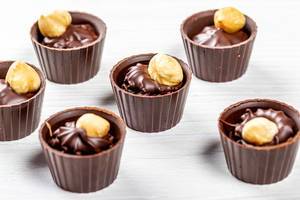Schöne Süßigkeiten: Haselnuss- und Milchschokoladenbonbons auf weißem Holzhintergrund