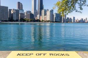 Schrift "Keep off rocks" am Ufer vom Michigansee mit Blick auf die Wolkenkratzer