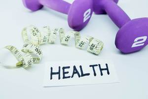 Schriftzug HEALTH neben Maßband und violetten Fitnesshanteln