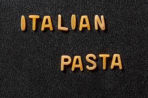 Schriftzug Italian Pasta aus Nudeln auf schwarzem Hintergrund