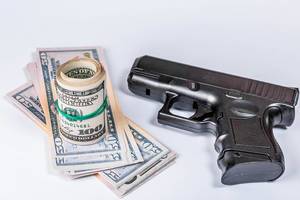 Schwarze Waffe und Geld in Dollarnoten auf einem weißen Hintergrund