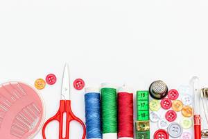 Scissors, thread, needles, pins, measuring tape and buttons on white background with free space