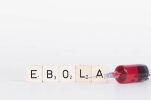 Scrabblesteine / Holzsteine ergeben das Wort Ebola, neben einer Spritze