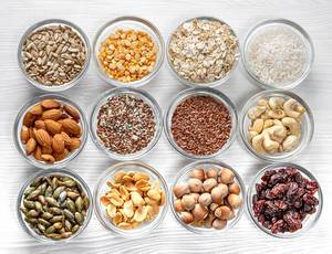 Seeds, nuts, grains in glass bowls on a white wooden background. Top view