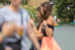 Seeroseanlagen mit Spritzwasser am See von Tomorrowland mit drinkenden Festivalbesucher im Vordergrund