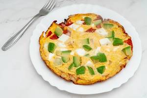 Serviertes Omelett mit Avocadostücken, Fetakäse und Tomaten