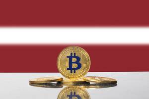 Set aus goldenen Bitcoin-Münzen vor der Flagge des baltischen Staates Lettland