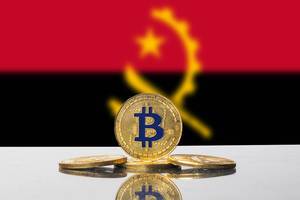 Set aus goldenen Bitcoins strahlt vor der Nationalflagge von Angola