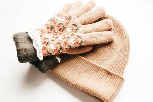 Set of knitted winter gloves and hat on white background