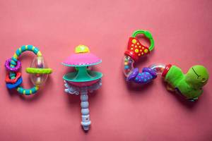 Set of plastic toys for newborn babies. Plastic rattle on the pink background. Flat lay photo.