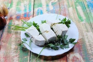 Sheep cheese and parsley on a white plate. Countryside wooden table