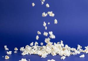 Shot of Popcorn falling against blue background
