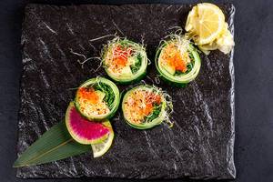 Sicht von oben auf ein Sushi-Set mit Krabbenfleisch, rotem Kaviar, Gurken und Microgreens-Keimsprossen