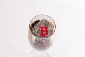 Silberner Bitcoin und Münzen im Champagnerglas