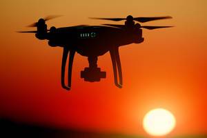 Silhouette of drone at sunset, orange sky