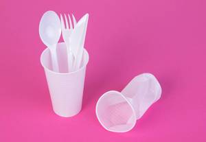 Single use plastic objects on pink background