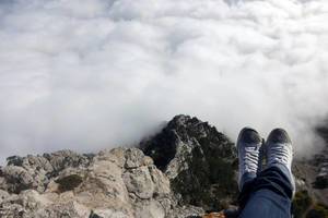 Sitting on the edge of the mountain with feet over an abyss. Ai-Petri mountain, Crimea